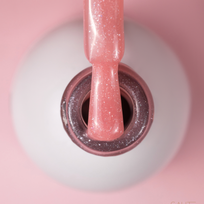 Frasco aberto de verniz das unhas rosa com brilho e pincel embebido