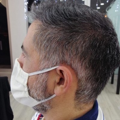 Homem de perfil usando máscara facial branca com elásticos para as orelhas em ambiente interior