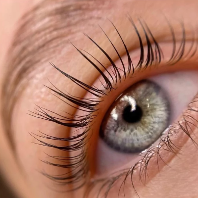 Close-up de um olho com pestanas longas e íris cinza esverdeada.