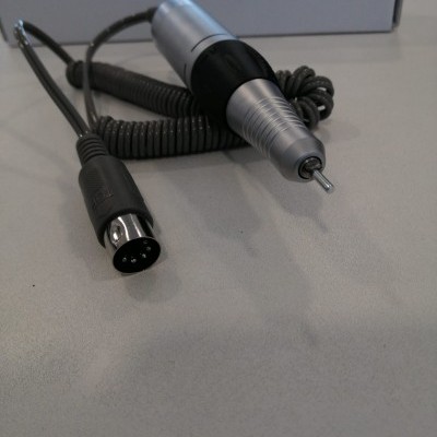 Pen digital metálico prateado com cabo espiral e conector preto em superfície branca