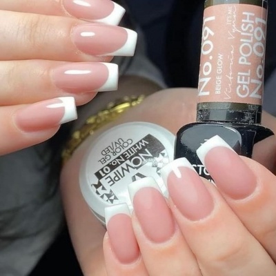 Unhas com gel francês e produtos de esmalte em câmera próxima