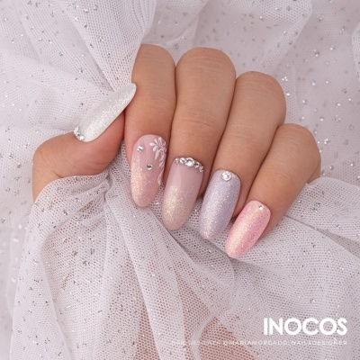 Unha decorada com cores pastel e brilhos, pedras e detalhe floral