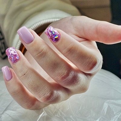 Mão feminina com unhas artificiais rosas e decoradas
