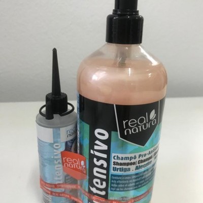 Dois produtos Real Natura para cabelos, champô e tónico, com frascos em plástico e rótulos com texto