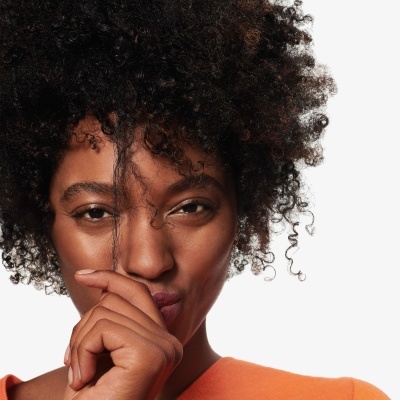 Mulher com camisola laranja e cabelo encaracolado