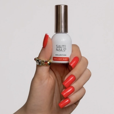 Verniz para unhas branco com tampa prateada segurado por mão com unhas vermelhas