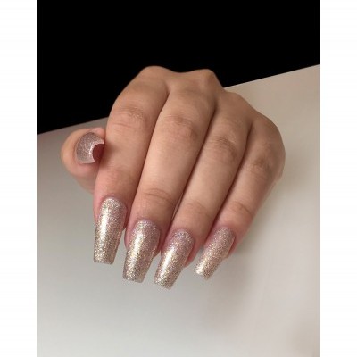 Mão com unhas longas quadradas e verniz dourado glitter