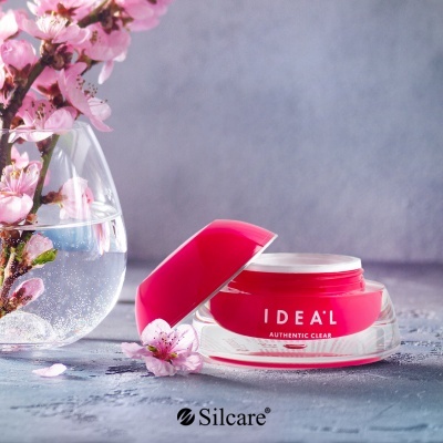 Frasco de creme rosa IDEAL ao lado de vaso com flores de cerejeira