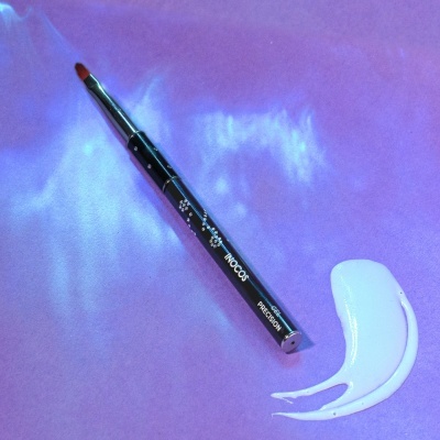 Pincel de maquilhagem preto com pincelada branca em fundo roxo