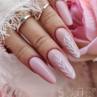Unhas compridas cor de rosa com decoração branca em fundo com flores e tecido