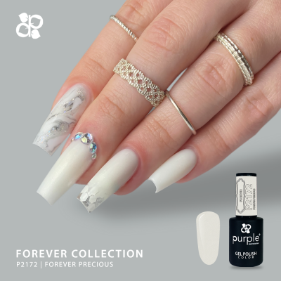 Mão com unhas postiças decoradas em branco, cinza e brilhantes junto a frasco de verniz gel