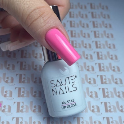 frasco branco de lip gloss SAUT NAILS com unha rosa brilhante segurando-o