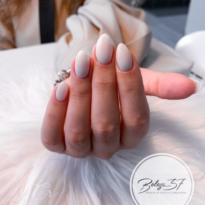 Unhas femininas amendoada pintadas de branco opaco sobre fundo branco peludo