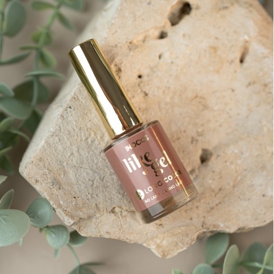 Frasco de esmalte de unhas rosa nude com tampa dourada sobre pedra clara