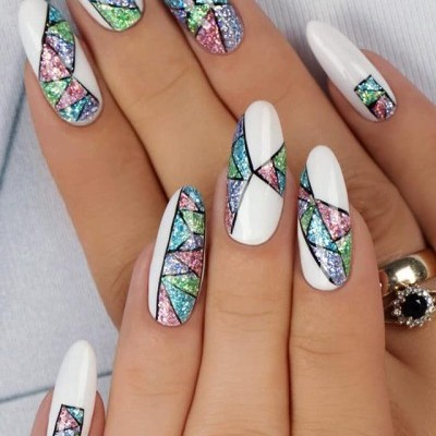 Unhas brancas com detalhes geométricos de glitter colorido em padrões variados.