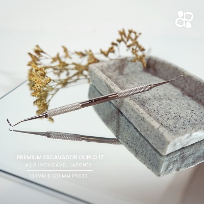 Ferramenta dupla de aço inoxidável sobre base de pedra cinzenta com ramo seco ao fundo