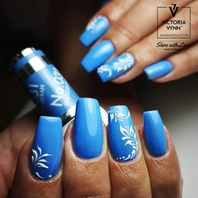 Unhas azuis com desenhos florais brancos segurando verniz