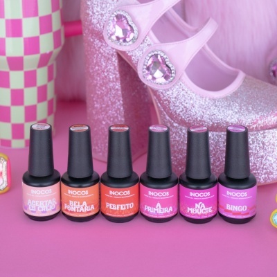 Seis frascos de verniz de unhas Inocos em cores variadas com sapato de salto rosa cintilante ao lado
