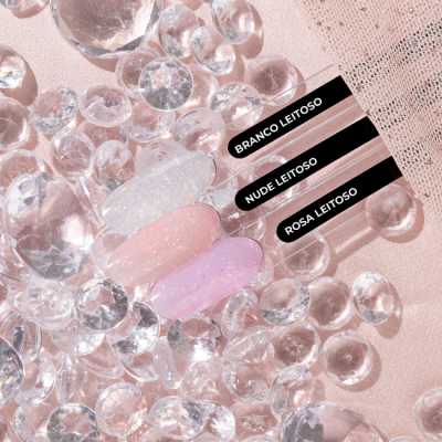 Vernizes de unhas em tons leitosos sobre pedras de vidro e tecido rosa com etiquetas pretas