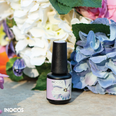 Frasco de verniz gel preto com rótulo violeta e flores ao fundo