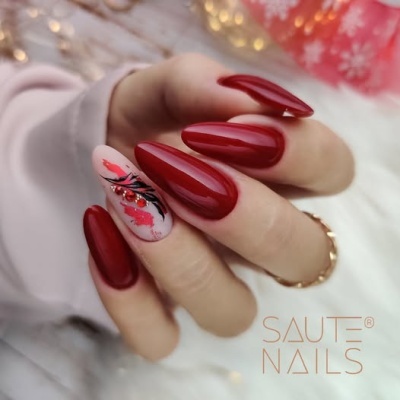 Mãos femininas com unhas vermelhas brilhantes e uma decorada, marca SAUTE NAILS no canto