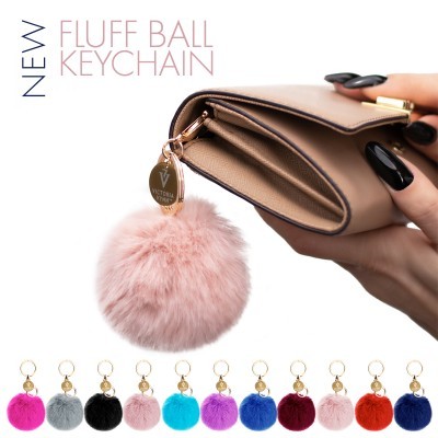 Porta-chaves com bola de pelo sintético cor de rosa claro junto a carteira bege e diversas bolas coloridas