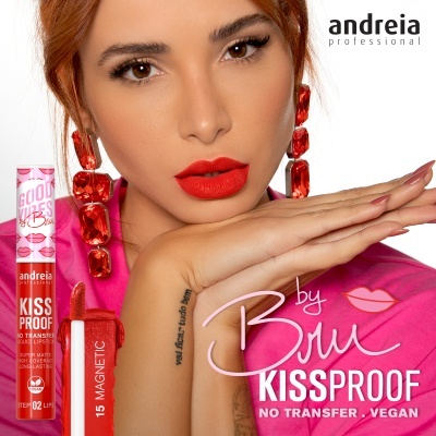 Mulher com batom vermelho, brincos vermelhos e roupa rosa com batom líquido andreia professional KISS PROOF no lado esquerdo.