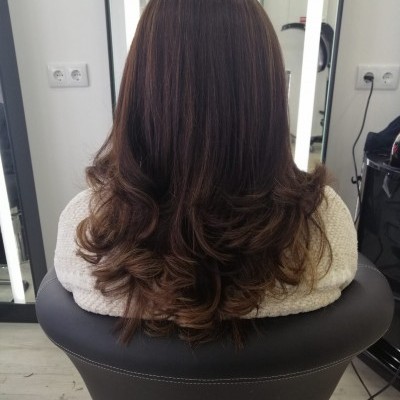 Cabelo castanho escuro com ondas nas pontas num salão de beleza com espelhos e iluminação