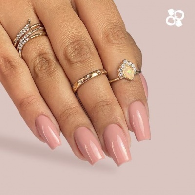 Mão feminina com unhas longas e anéis dourados e com pedras