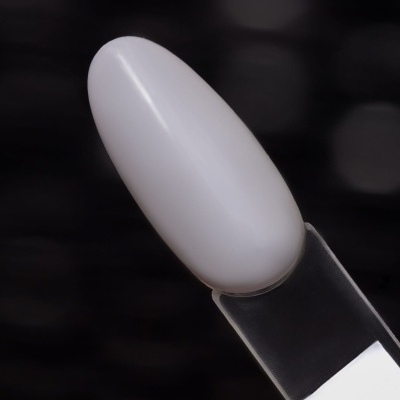 Amostra de verniz de unhas branca em base transparente sobre fundo desfocado preto.