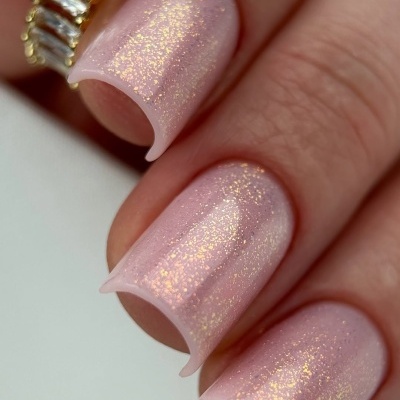 Unhas artificiais com verniz rosa claro e glitter dourado, anel dourado com pedras