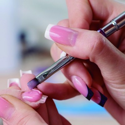 Aplicação de verniz rosa com pincel metálico em unhas femininas longas com ponta branca