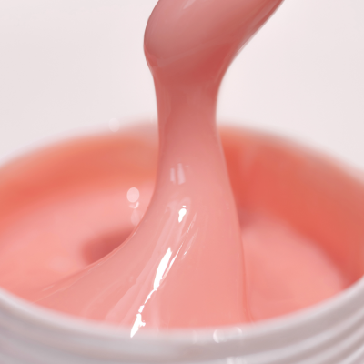 Gel ou verniz cor de rosa claro em pote branco com textura viscosa e brilhante
