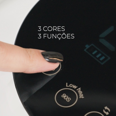 Dispositivo preto com visor digital e botão pressionado por dedo com unha preta