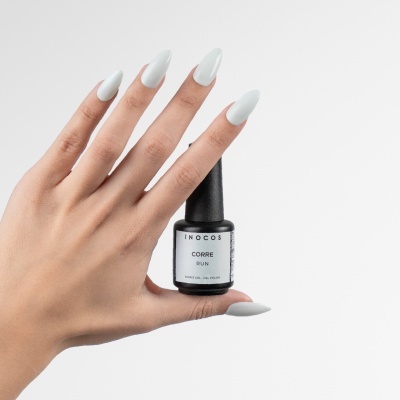 Mão com unhas pintadas de branco segurando frasco de verniz gel Inocos