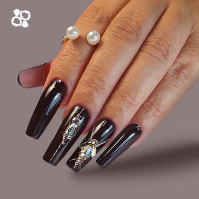 Unha negra com decoração prateada e strass em mão feminina com anel de pérolas