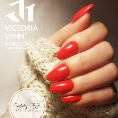 Mão com unhas vermelhas brilhantes segurando malha branca com texto Victoria Vynn e Beleza 57