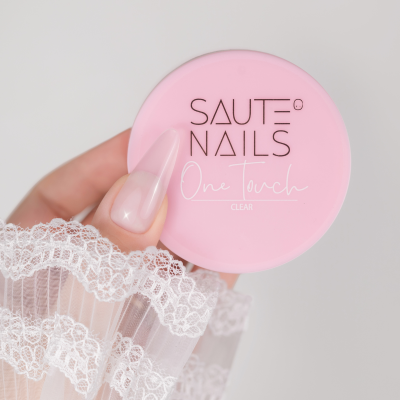 Frasco redondo rosa SAUTE NAILS com unhas em gel rosa translúcido e manga de renda