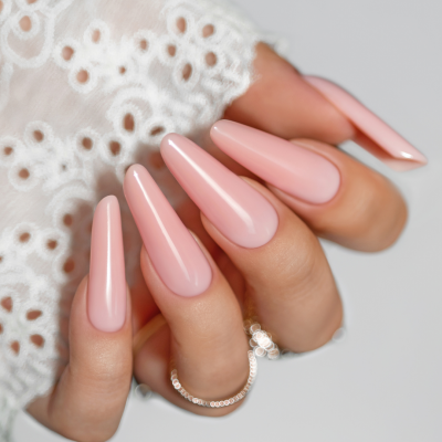 Mão com unhas longas cor-de-rosa nude brilhante e anéis delicados