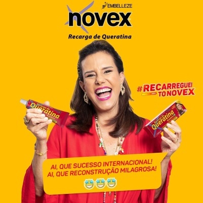 Mulher sorridente segurando embalagens do Novex Recarga de Queratina com fundo amarelo