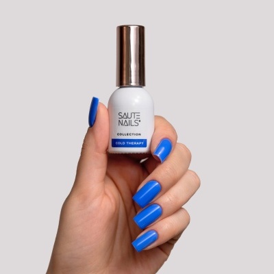 Frasco branco de verniz para unhas com tampa metalizada, segurado por mão com unhas azuis