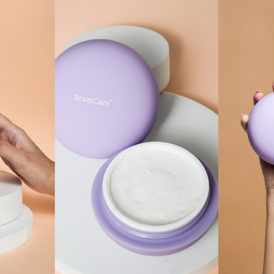 Creme hidratante em recipiente lilás com tampa, detalhe do creme branco e mãos femininas a tocar e segurar o produto