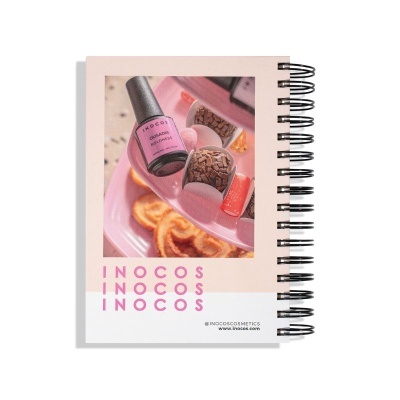 Caderno espiral com capa decorada com imagem de verniz de unha rosa e texto INOCOS