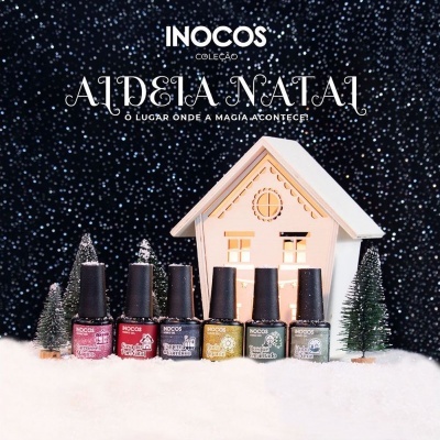 Seis vernizes INOCOS coleção Aldeia Natal em frente a casinha branca e árvores de Natal na neve.