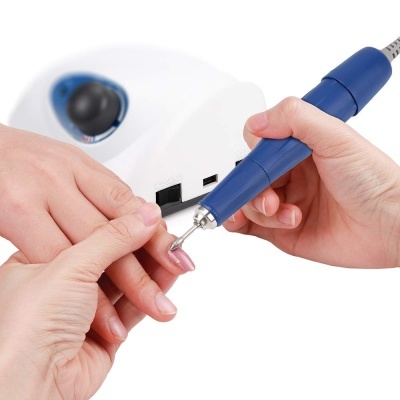 Aparelho elétrico azul para manicure ligado a base branca usada numa mão para tratar outra unha