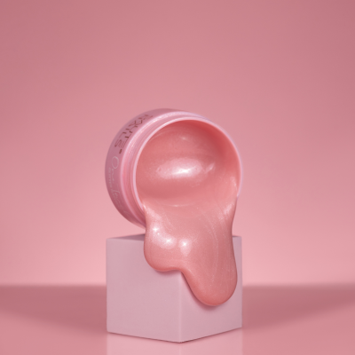 Frasco rosa de verniz a escorrer sobre cubo rosa com fundo rosa