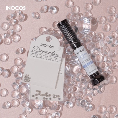 Produtos para unhas INOCOS com cristais transparentes sobre fundo rosa claro