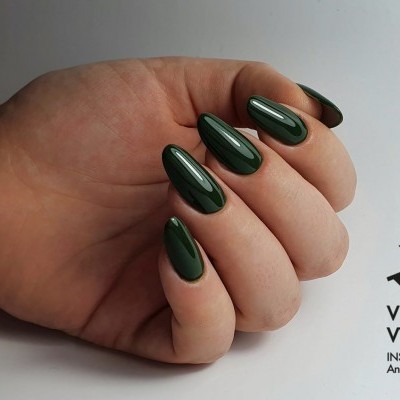 Mão com unhas verdes escuras brilhantes em fundo cinza claro com logo Victoria Vynn