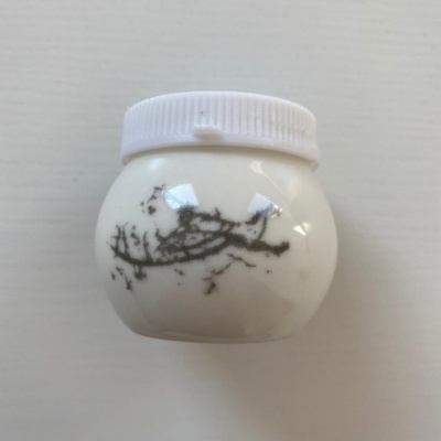 Frasco plástico branco com tampa branca e mancha preta irregular