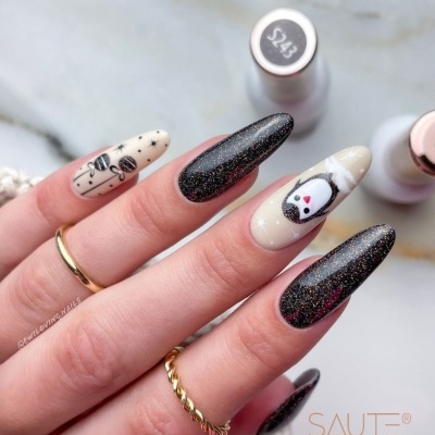 Unhas decoradas em preto brilhante e bege com desenhos natalícios, frascos de verniz e texto SAUTE NAILS